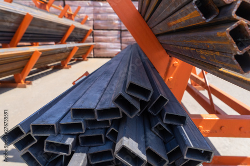 Square steel pipes, stacked on a special stand. Perspective.