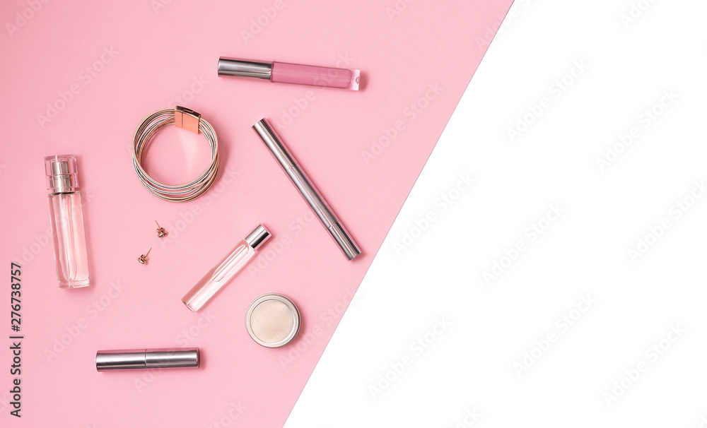 Flat lay composition with decorative makeup products and gold chain necklace on pastel pink background. Makeup and beaty concept. Copy space.