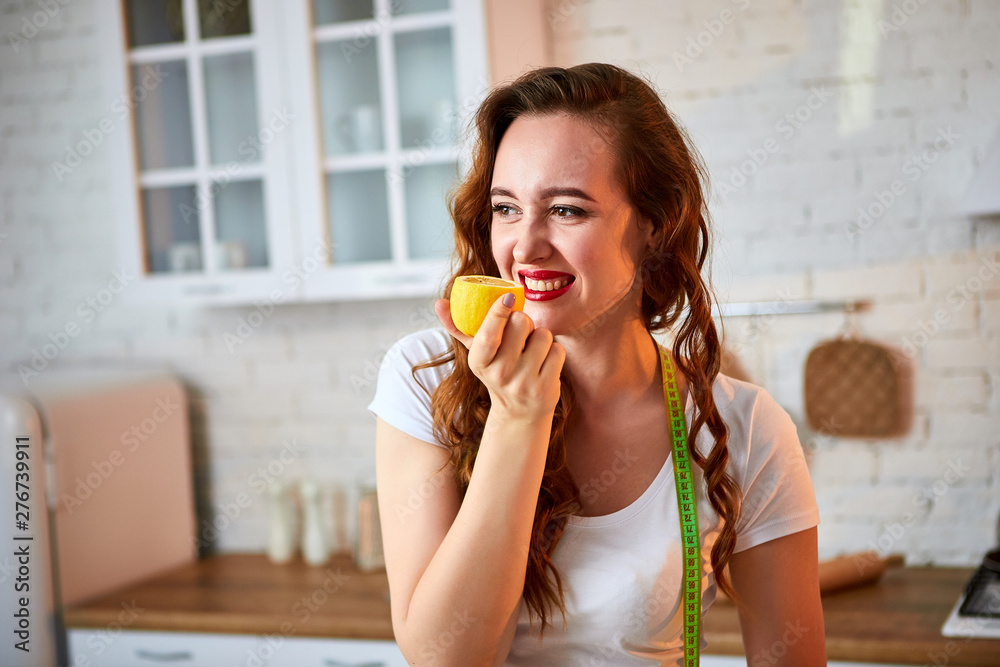 Young happy woman with orange and lemon (citrus) in modern kitchen. Healthy food and Dieting concept. Loosing Weight Young happy woman with orange and lemon (citrus) in modern kitchen. Healthy food and Dieting concept. Loosing Weight