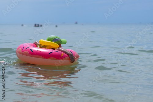 A 3-year-old boy swims in the sea in a life jacket and rubber ring. Persons not visible. Early morning.