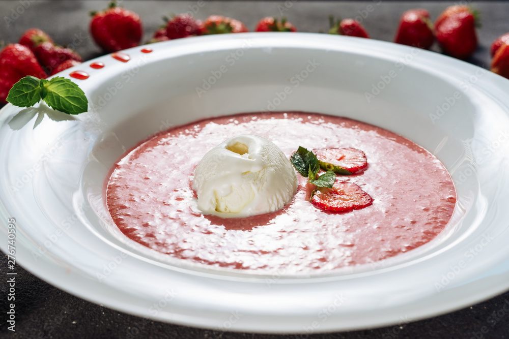 Strawberry Gazpacho Summer Meal with Ice Cream. Frosty Breakfast Creamy Soup Dessert Made of Blended Natural Red Berries in Ceramic Plate Decorated Green Leaves. Cool Classic Spanish Cuisine Closeup Strawberry Gazpacho Summer Meal with Ice Cream. Frosty Breakfast Creamy Soup Dessert Made of Blended Natural Red Berries in Ceramic Plate Decorated Green Leaves. Cool Classic Spanish Cuisine Closeup