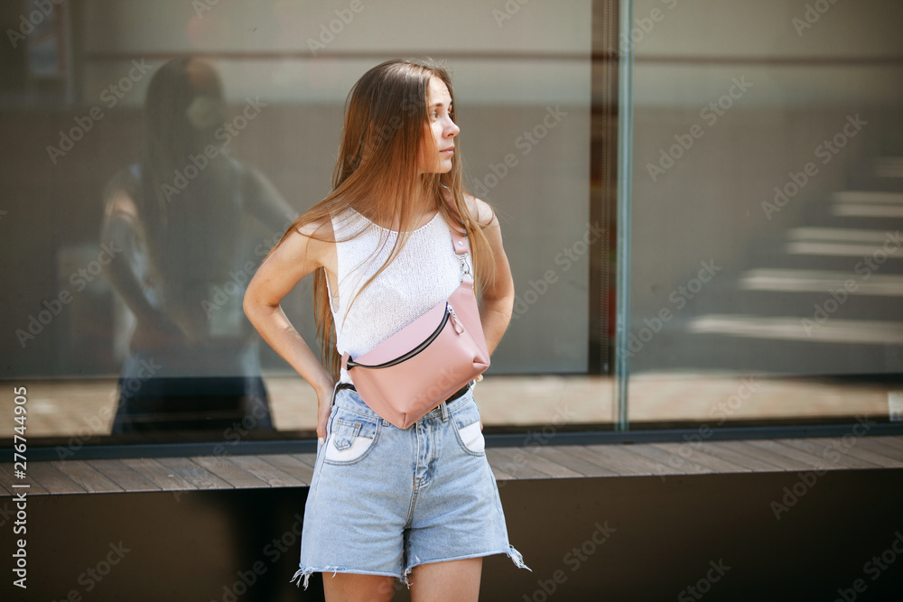 Beautiful slim girl in denim shorts looks into the distance. Beautiful slim girl in denim shorts looks into the distance.
