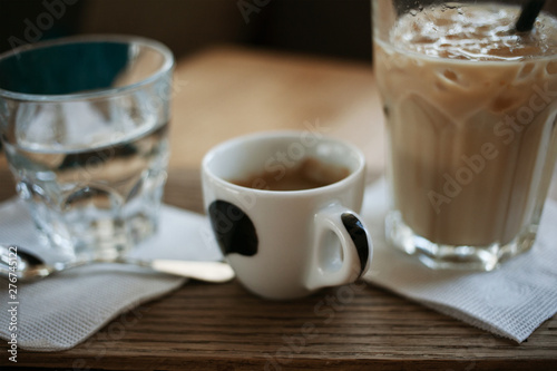 Coffee break concept. Morning habits. A cup of espresso and a glass of ice latte on a brown wooden table.