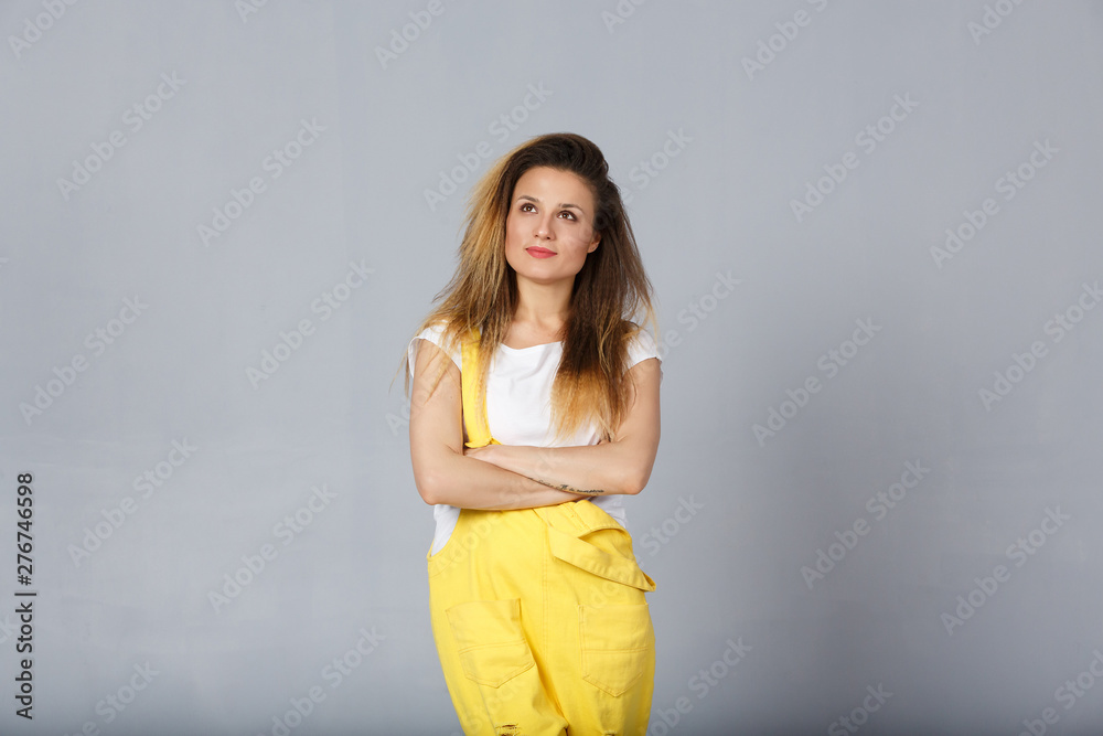 Studio shot of young woman with appealing appearance, has concentrated and dreamful look aside, thinks about future, poses against grey background with blank copy space for your text Studio shot of young woman with appealing appearance, has concentrated and dreamful look aside, thinks about future, poses against grey background with blank copy space for your text