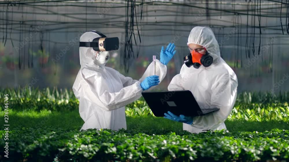 A biologist is holding a tube and talking to another specialist. Poison, pesticide in food concept. A biologist is holding a tube and talking to another specialist. Poison, pesticide in food concept.
