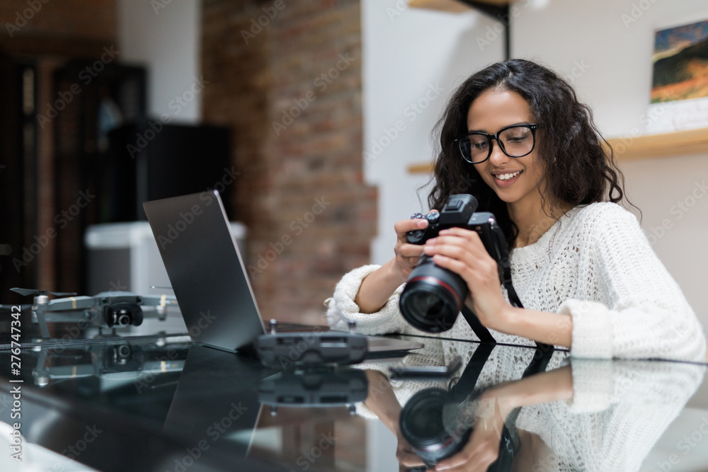 Young pretty woman photographer processing pictures sitting on the desk Young pretty woman photographer processing pictures sitting on the desk