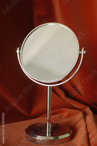 Beautiful female mirror on a velvet brown fabric background. Mirror without reflection. Cosmetic accessories for your catalog. Layout for professional makeup artist. Fabric folds