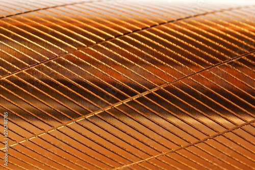A fragment of a metal object with diagonal notches and a golden hue. Background and pattern