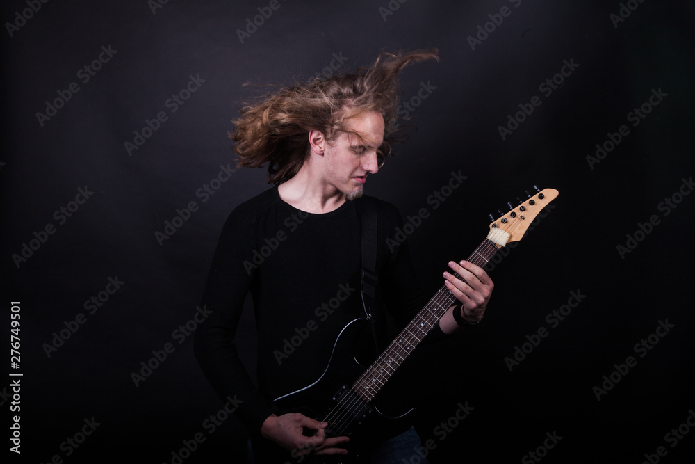 Obraz premium Young caucasian adult playing guitar in the studio