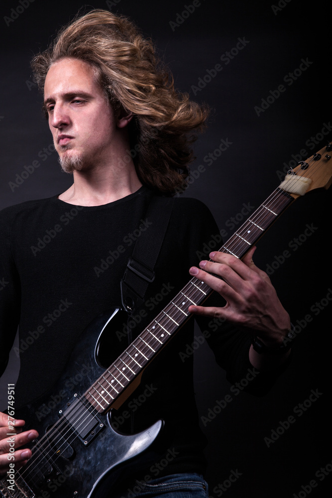 Obraz premium Young caucasian adult playing guitar in the studio