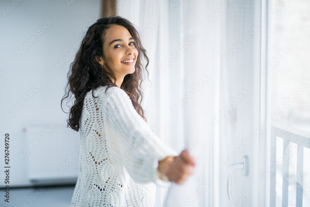 People and hope concept. Happy woman opening window curtains