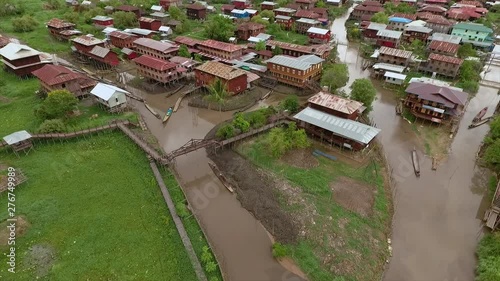 Medium high-angle zoom-in pan shot of Nampan floating village stilt houses interlinked by Inle Lake water channels, and hand-made bridges in Inle Lake, Nampan Village, Shan State, Myanmar photo