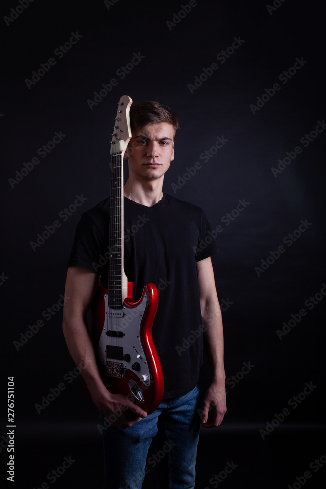 Obraz premium Young caucasian adult holding guitar in the studio