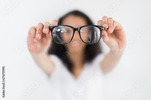 Glasses optician showing eyewear. Closeup of glasses, with glasses and frame in focus. Woman holding and pointed glasses on white background.