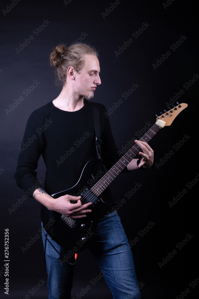 Obraz premium Young caucasian adult playing guitar in the studio