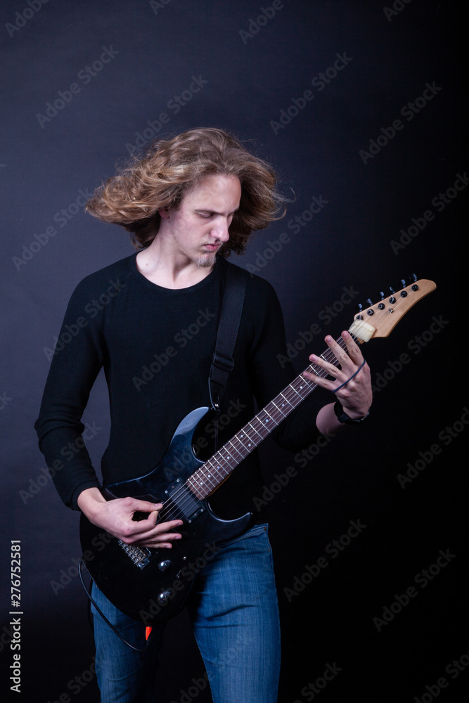 Young caucasian adult playing guitar in the studio