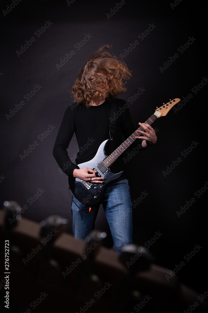 Obraz premium Young caucasian adult playing guitar in the studio