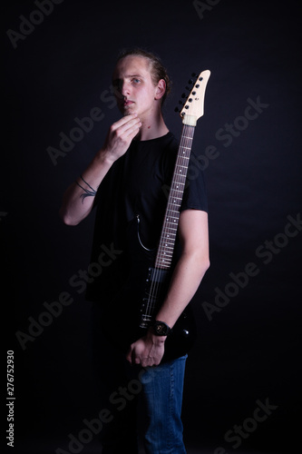 Young caucasian adult posing with electric guitar in the studio