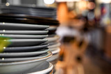 Closeup stack of white and colored blue porcelain plates with oriental and ethnic ornament stands in open kitchen of trendy restaurant. Concept washing dishes, preparing for lunch, evening service