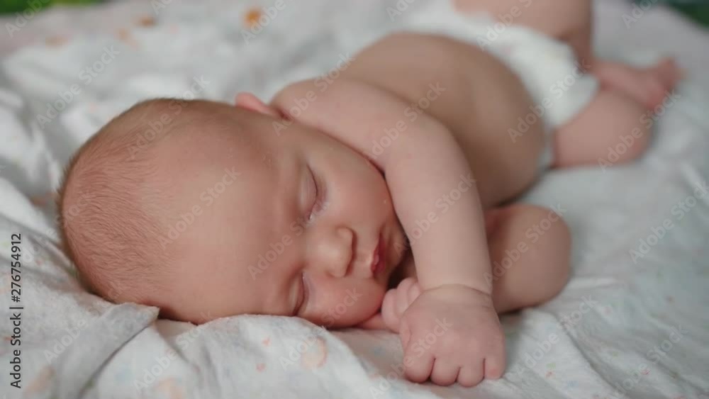 Cute 2 weeks old newborn baby is sleeping on the bed. Close up shot. Cute 2 weeks old newborn baby is sleeping on the bed. Close up shot.