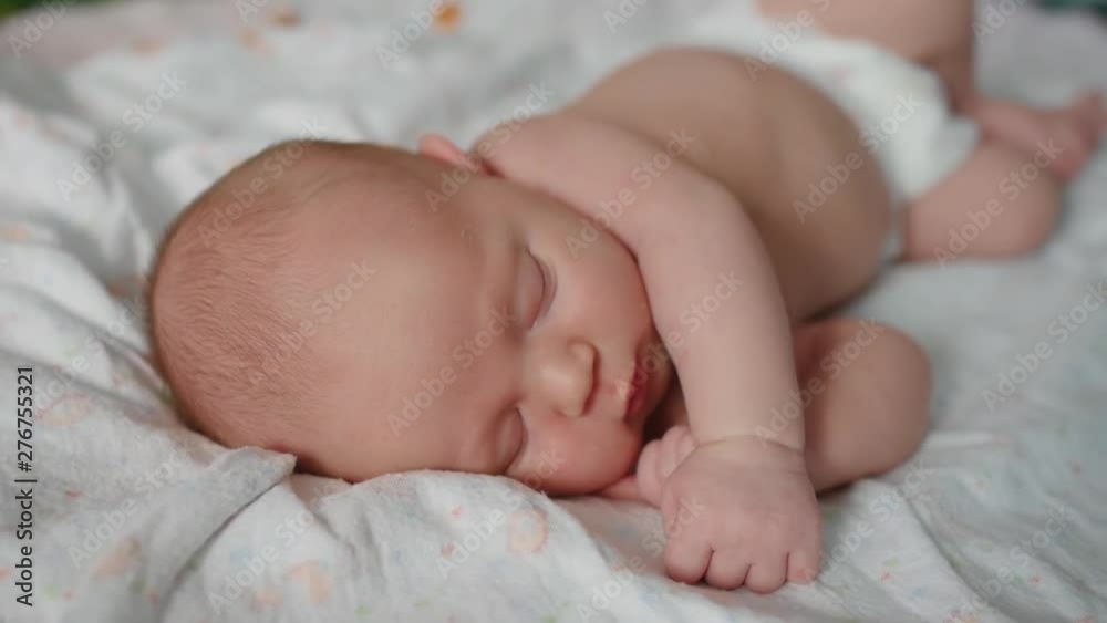Cute 2 weeks old newborn baby is sleeping on the bed. Close up shot. Cute 2 weeks old newborn baby is sleeping on the bed. Close up shot.
