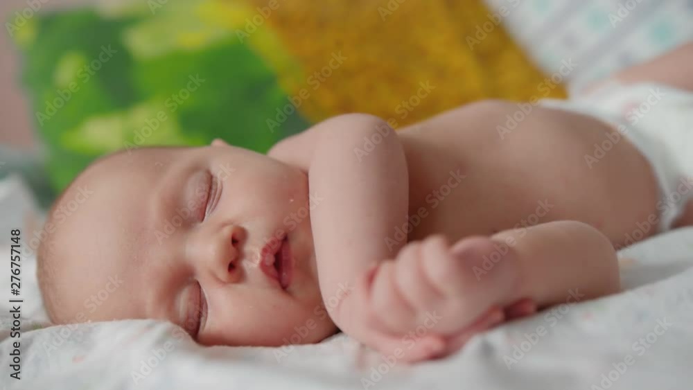 Cute 2 weeks old newborn baby is sleeping on the bed. Protection of children. Newborn health. Close up shot. Cute 2 weeks old newborn baby is sleeping on the bed. Protection of children. Newborn health. Close up shot.