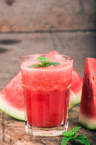 A glass of fresh watermelon juice on a wooden board background