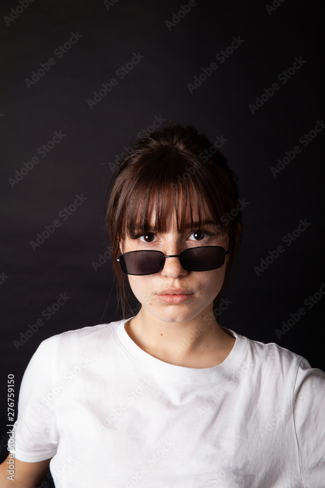 Caucasian Girl in white shirt with black sunglasses posing in the studio Caucasian Girl in white shirt with black sunglasses posing in the studio