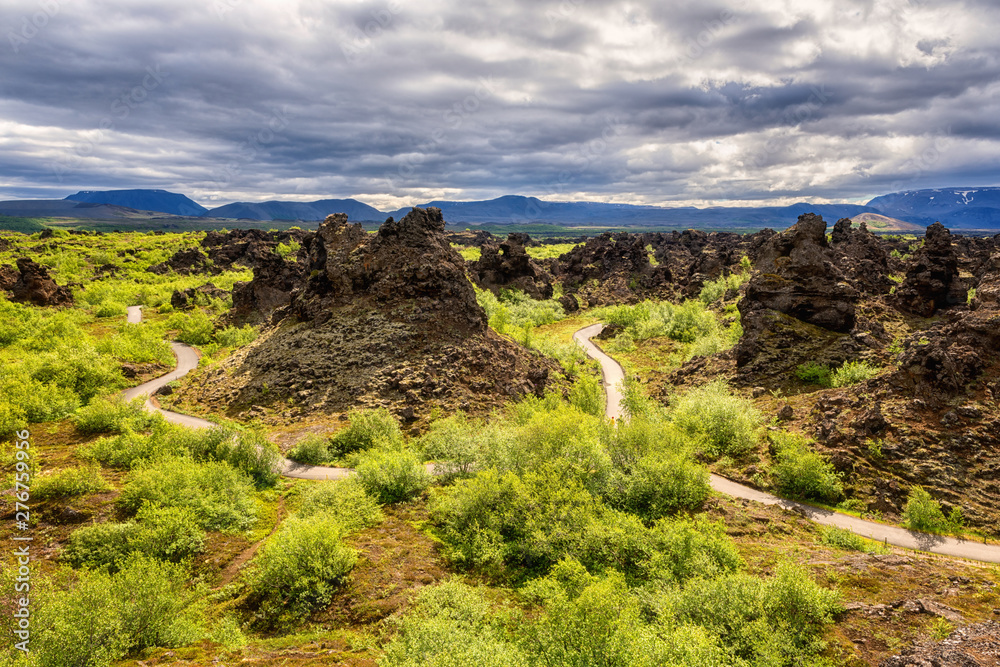 Dimmuborgir lava fields near Myvatn in Iceland. Amazing nature landscape, panoramic view of popular tourist attraction - green valley, rock formations and blue cloudy sky, outdoor travel background