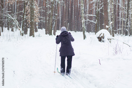 a woman in the winter time goes skiing. View from the back