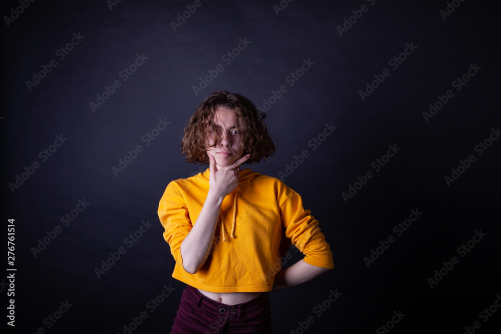 Young caucasian highschool girl in yellow hoodie posing in the studio