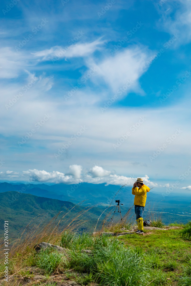 Tourists stand to take pictures at the viewpoint with mountains and beautiful skies