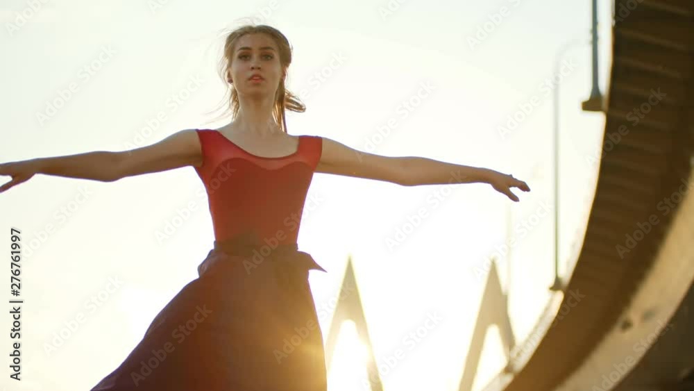 Young woman ballerina dancing under the bridge on sunset - performing turns Young woman ballerina dancing under the bridge on sunset - performing turns