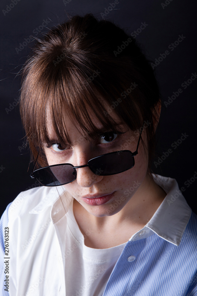 Caucasian Girl in white shirt with black sunglasses posing in the studio Caucasian Girl in white shirt with black sunglasses posing in the studio