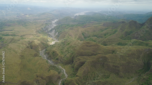 Aerial view of mountains covered with green vegetation, trees in vicinity volcano Pinatubo. Slopes of mountains, sky and clouds. Cordillera region. Luzon, Philippines.