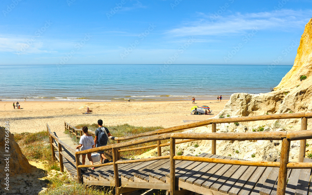 Φωτογραφία A couple walking down the wooden walkway towards the Asperillo beach, very close