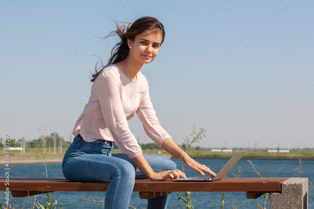 Young woman with a laptop on a park bench