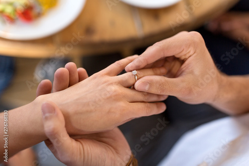 proposal, engagement and relationships concept - close up of man putting diamond ring to female hand at restaurant © Syda Productions