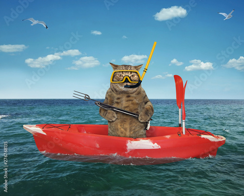 The cat underwater hunter in uniform with a speargun is dfifting in the red plastic boat in the sea.