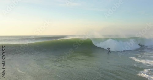 Drone aerial top down view / perspective of a Surfer catching a large wave while trying to race ahead of the crashing white water to stay on his surfboard photo