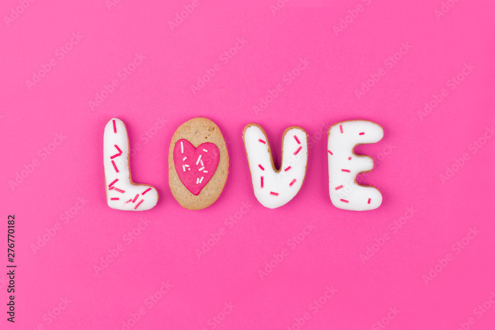 Gingerbread in the shape of the word love on a pink background. Flat lay, top view.
