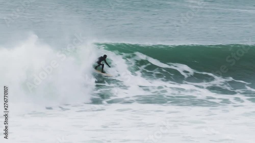 Surfer catches a big wave in the cold water on a longboard going right in clean offshore conditions on a big day in porthleven cornwall photo