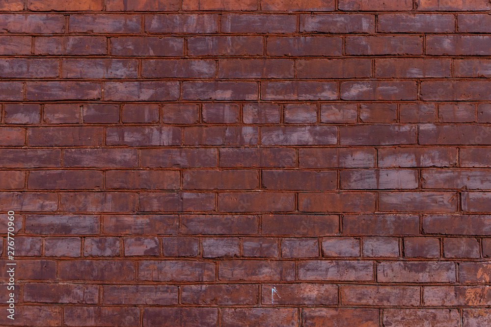 Old red painted brick wall with beautiful rows of speckled bricks.