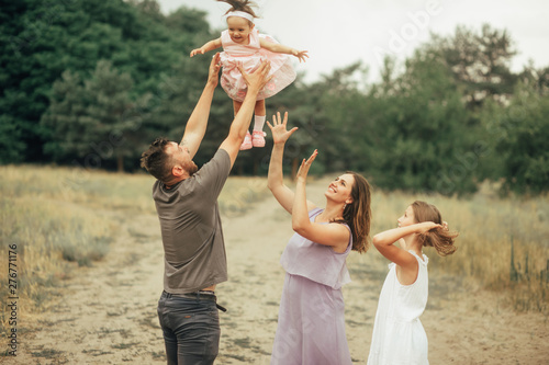 Happy family has fun on a walk and throws up their daughter.