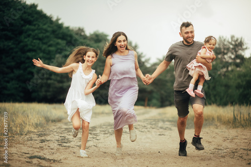 Happy family has fun, runs and laughs on a walk.