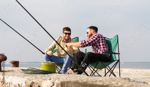 leisure and people concept - happy male friends with smartphone fishing and drinking beer