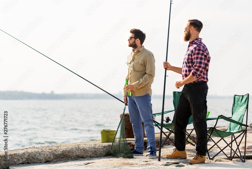 leisure and people concept - male friends with fishing rods and beer on pier at sea leisure and people concept - male friends with fishing rods and beer on pier at sea