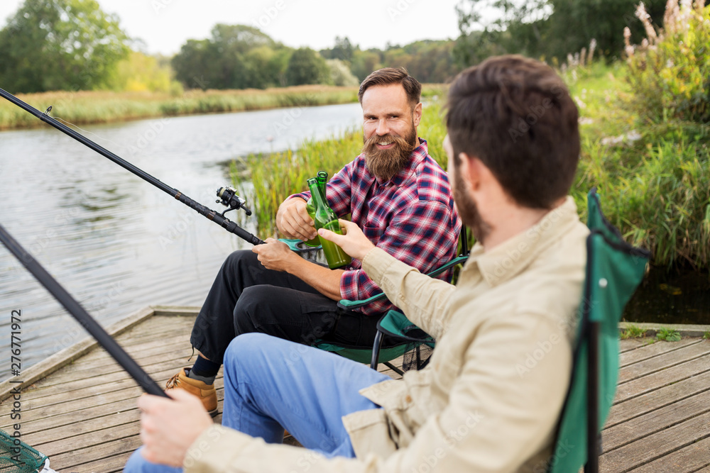 leisure and people concept - happy friends fishing and drinking beer on pier leisure and people concept - happy friends fishing and drinking beer on pier