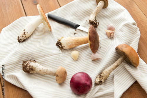 cooking and harvest concept - different edible mushrooms, kitchen knife and towel on wooden table