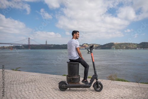 Male model in font of river with scooter